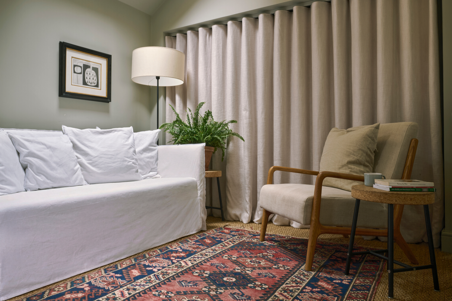Jack Gourlay's therapy room with a green velvet sofa, patterned rug and framed artwork