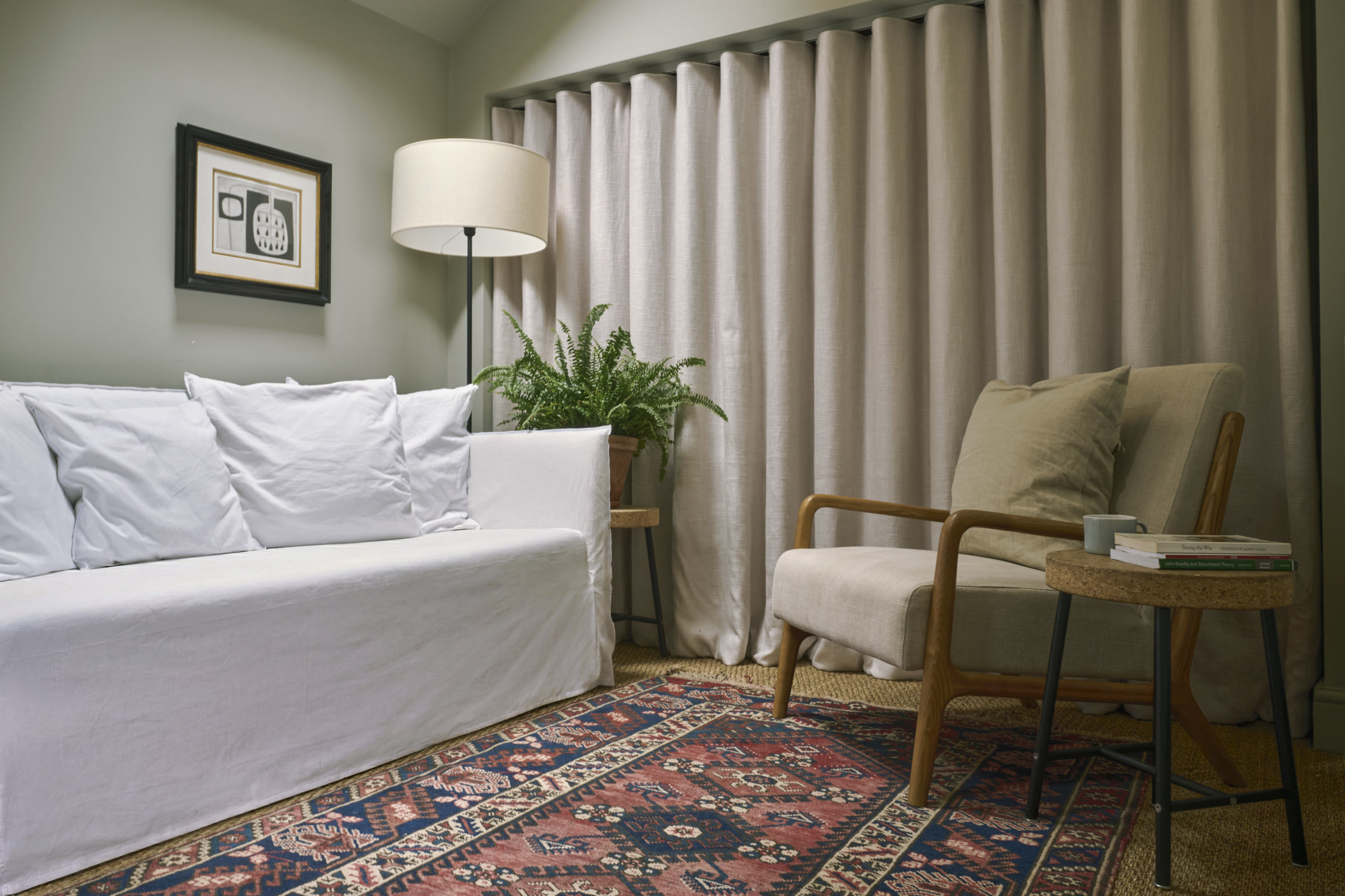 Jack Gourlay's therapy room with a white sofa, armchair, floor lamp, plant and patterned rug