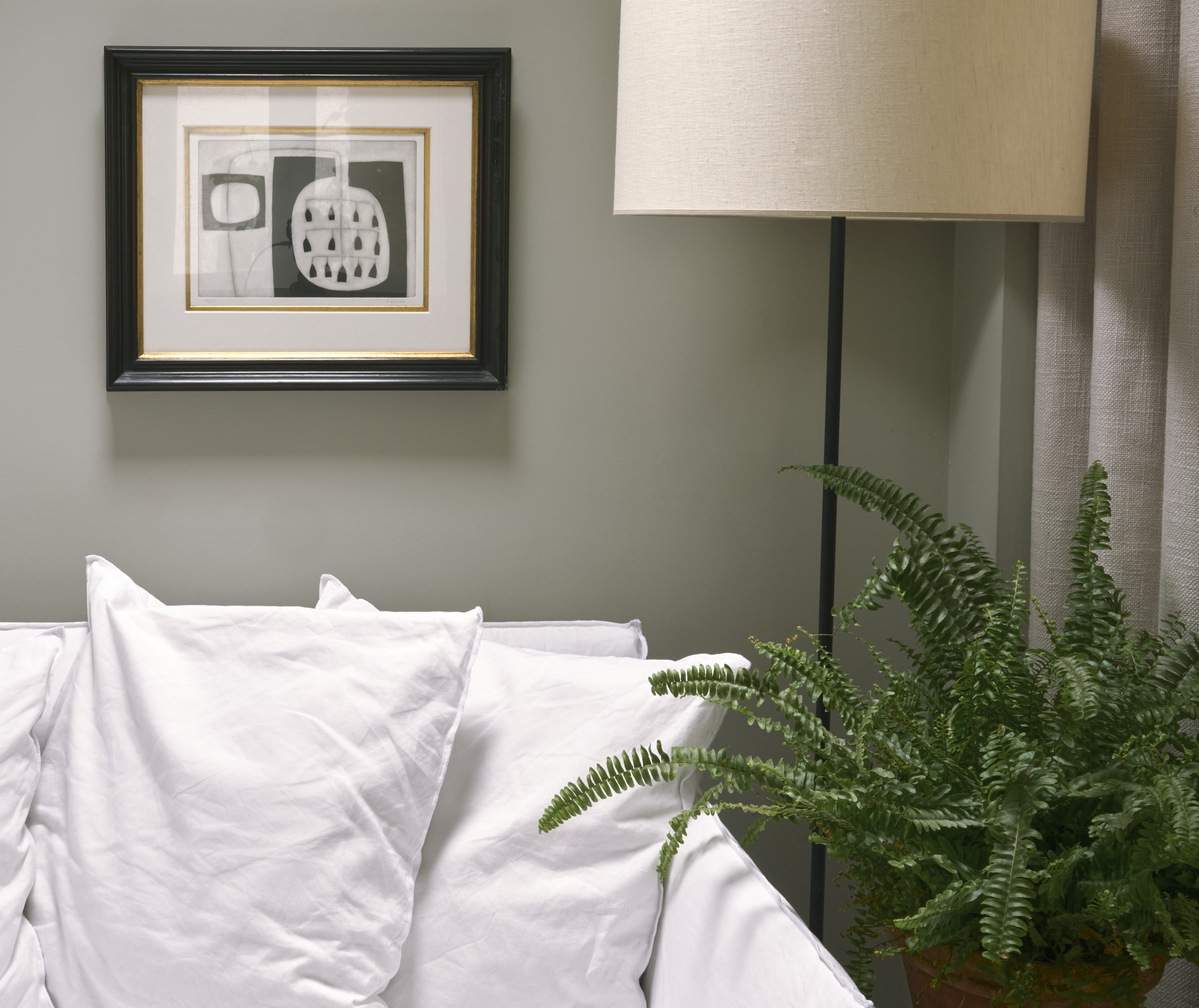 Calm therapy room detail with white linen cushions, a floor lamp, and a leafy plant